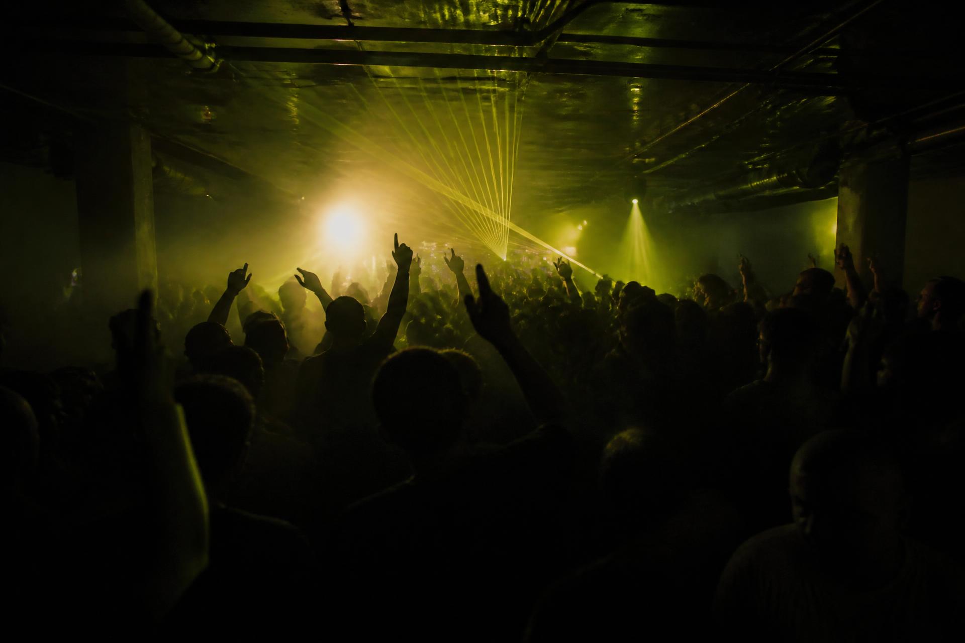 Crowd dancing on a dark Sydney nightclub dancefloor lit by lasers and haze
